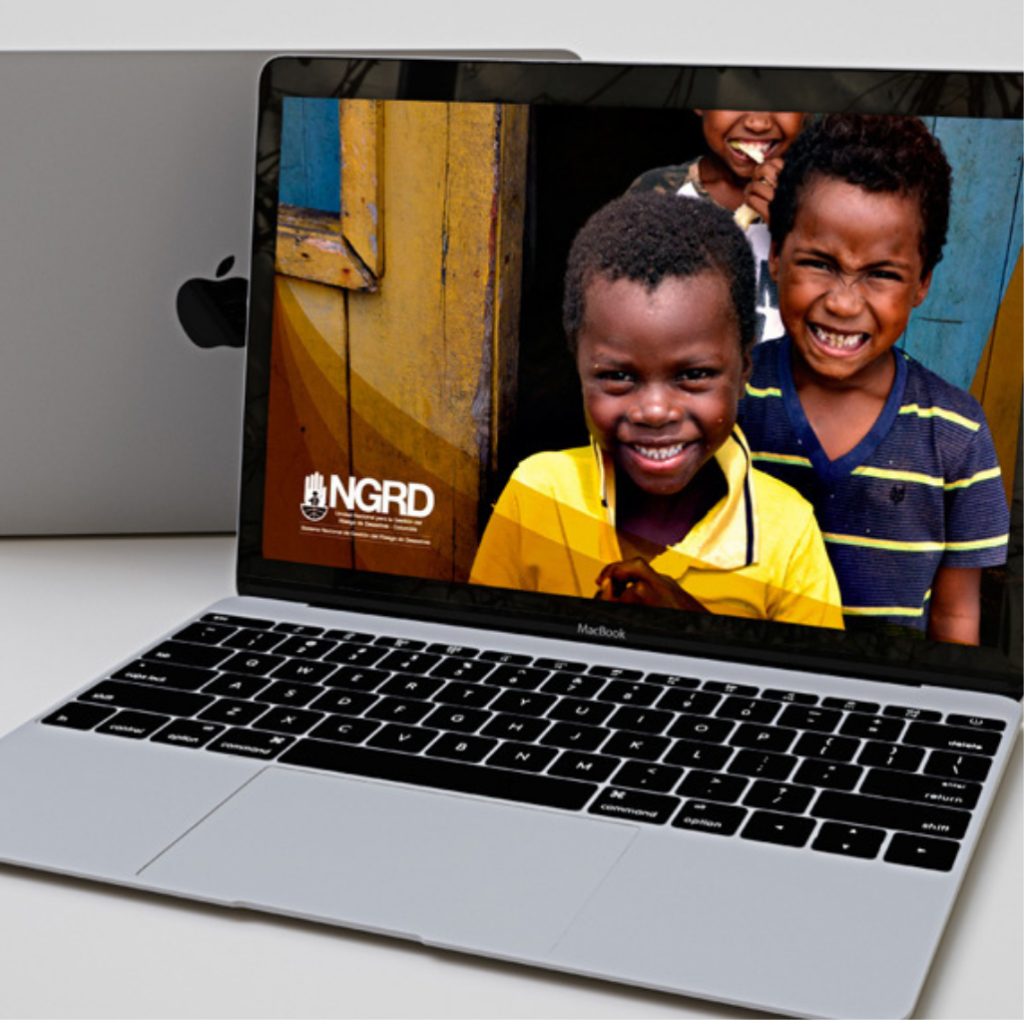Mockup de una computadora portátil MacBook abierta que muestra en su pantalla el diseño de un sitio web institucional con el logotipo de la UNGRD y la fotografía de niños sonriendo.